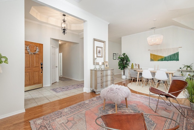 interior space with visible vents, wood finished floors, baseboards, a notable chandelier, and ornamental molding
