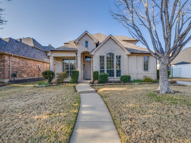 traditional home with brick siding, roof with shingles, and a front lawn