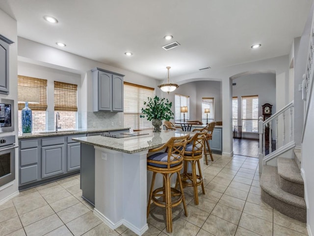 kitchen featuring visible vents, light stone countertops, gray cabinetry, a sink, and stainless steel appliances
