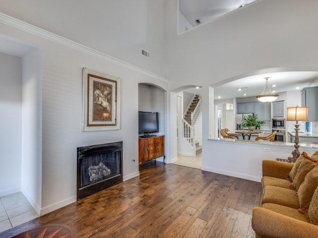 living area with a fireplace, wood-type flooring, arched walkways, visible vents, and stairway