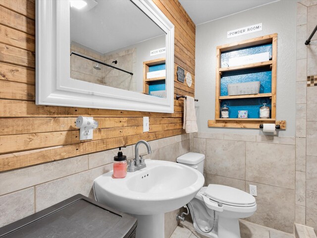 bathroom with a sink, tile walls, toilet, and a shower