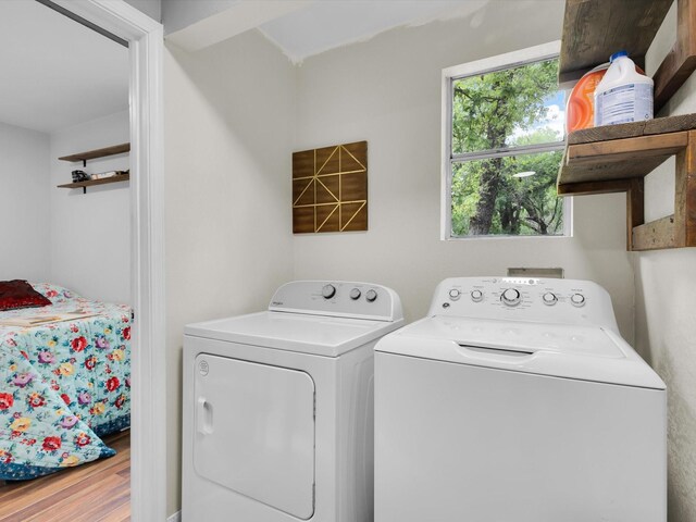 washroom featuring laundry area, wood finished floors, and washing machine and clothes dryer