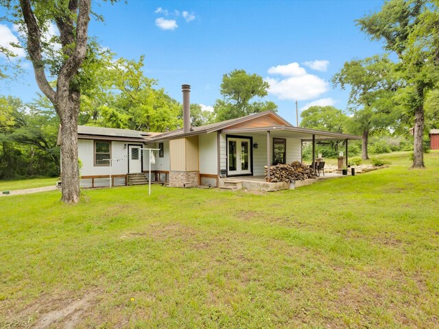rear view of house with a lawn, entry steps, and solar panels