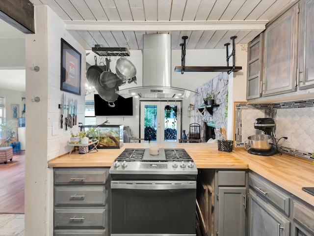 kitchen with island exhaust hood, butcher block counters, gray cabinets, and stainless steel gas stove