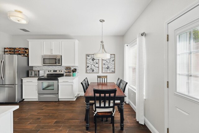 kitchen with appliances with stainless steel finishes, decorative backsplash, white cabinets, and visible vents