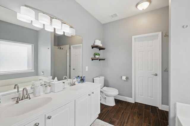 full bath with wood finish floors, visible vents, a sink, and a bath