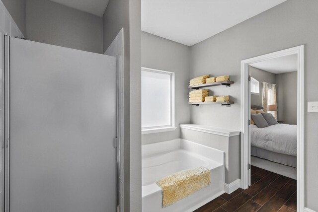 full bath with connected bathroom, a wealth of natural light, a bath, and wood finished floors