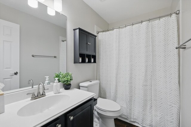 full bath featuring toilet, a shower with shower curtain, and vanity