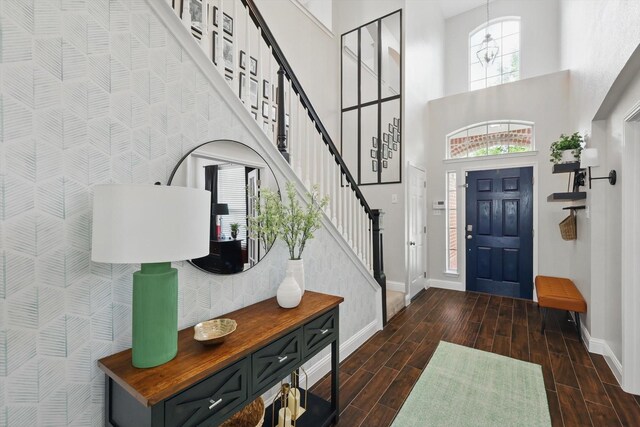 entryway featuring baseboards, stairs, a towering ceiling, and dark wood finished floors