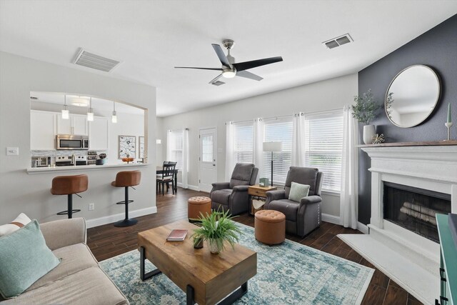 living area featuring baseboards, ceiling fan, and visible vents