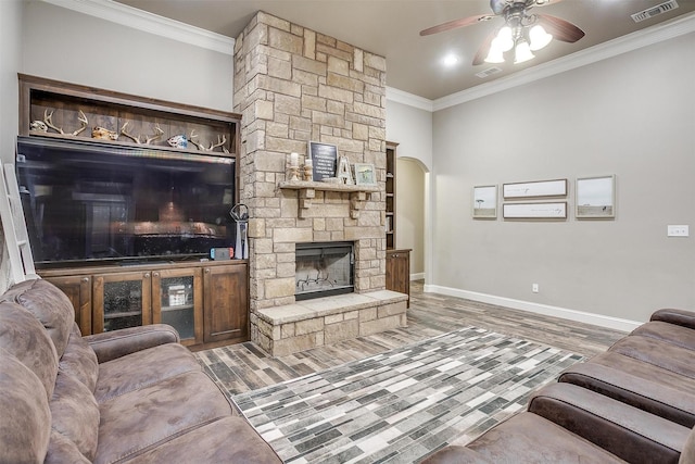 living area featuring a ceiling fan, baseboards, wood finished floors, visible vents, and ornamental molding