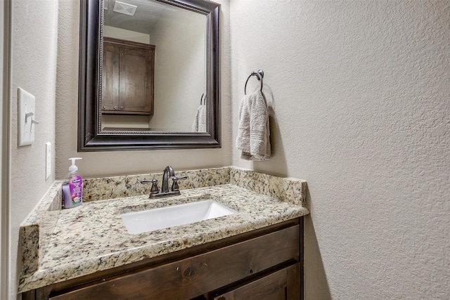 bathroom with a textured wall and vanity