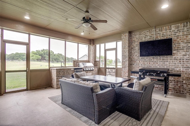 sunroom / solarium featuring a sink, a ceiling fan, finished concrete flooring, and exterior kitchen