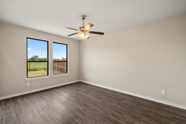 unfurnished room with ceiling fan, baseboards, and dark wood-type flooring