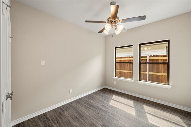 spare room featuring a ceiling fan, baseboards, and dark wood-style floors