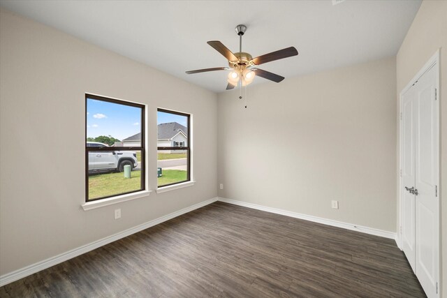 unfurnished bedroom featuring dark wood-style flooring, baseboards, ceiling fan, and a closet