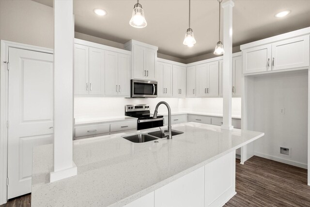 kitchen with white cabinets, light stone countertops, hanging light fixtures, appliances with stainless steel finishes, and a sink