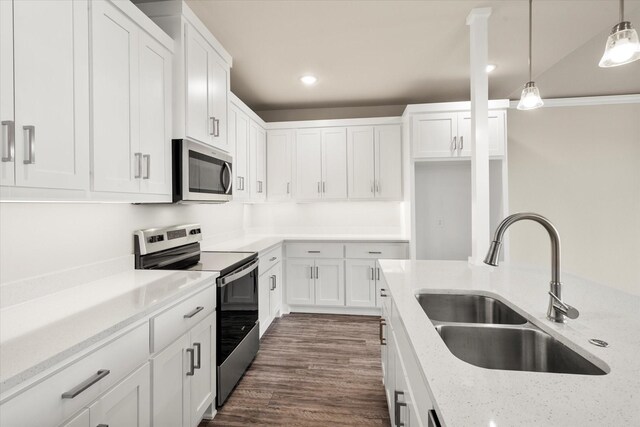 kitchen featuring light stone countertops, white cabinetry, a sink, appliances with stainless steel finishes, and decorative light fixtures