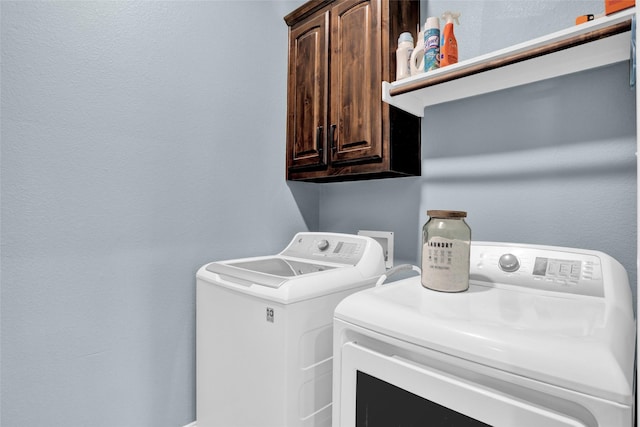 clothes washing area featuring washing machine and dryer and cabinet space