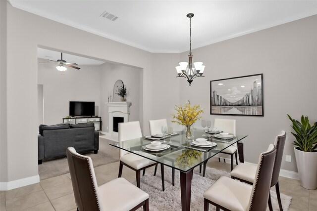 dining space with light tile patterned floors, baseboards, ornamental molding, visible vents, and ceiling fan with notable chandelier