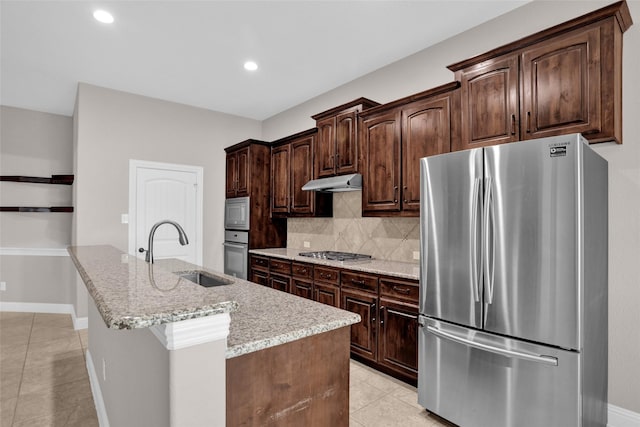 kitchen with under cabinet range hood, light tile patterned floors, a sink, decorative backsplash, and stainless steel appliances
