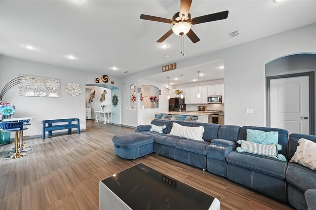 living room with ceiling fan, arched walkways, recessed lighting, wood finished floors, and visible vents