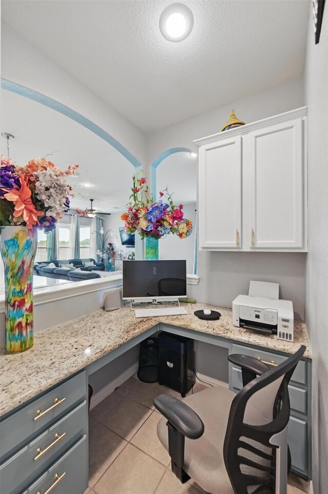 office space featuring a textured ceiling, built in desk, and light tile patterned floors
