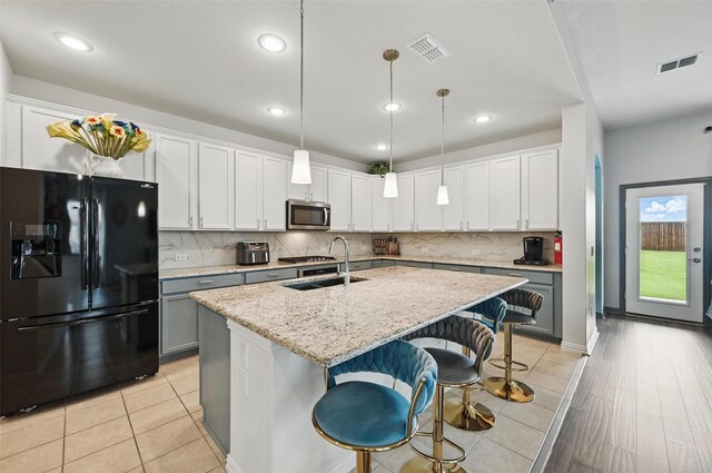 kitchen with appliances with stainless steel finishes, a center island with sink, a sink, and visible vents