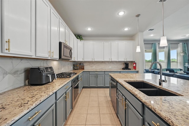 kitchen featuring white cabinets, a sink, gray cabinets, stainless steel appliances, and tasteful backsplash