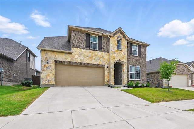 traditional home featuring central AC unit, concrete driveway, a front yard, and stone siding