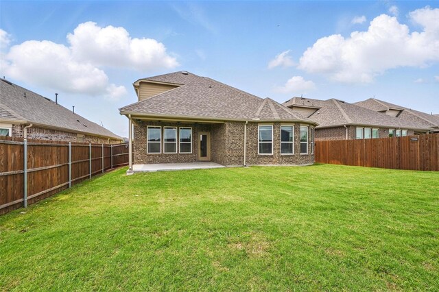 rear view of property featuring a patio, a fenced backyard, a lawn, and brick siding