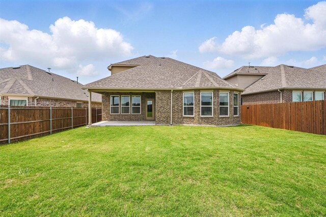 rear view of property with a lawn, brick siding, a fenced backyard, and a patio area