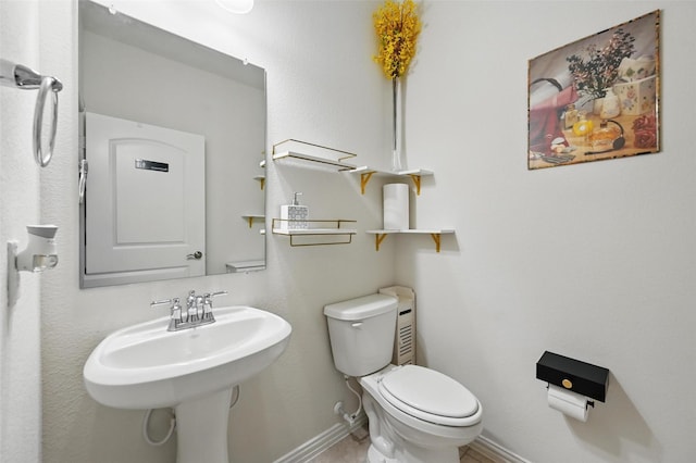 bathroom with a sink, baseboards, and toilet