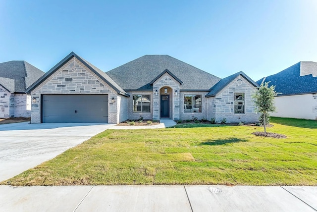 french country home featuring a garage, driveway, a front lawn, and stone siding