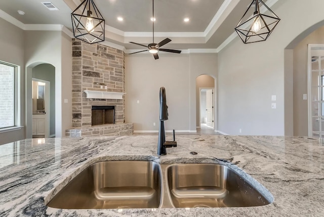 kitchen featuring light stone countertops, a sink, a ceiling fan, open floor plan, and visible vents