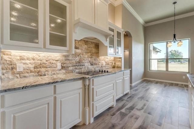 kitchen with black electric stovetop, white cabinetry, decorative backsplash, ornamental molding, and glass insert cabinets