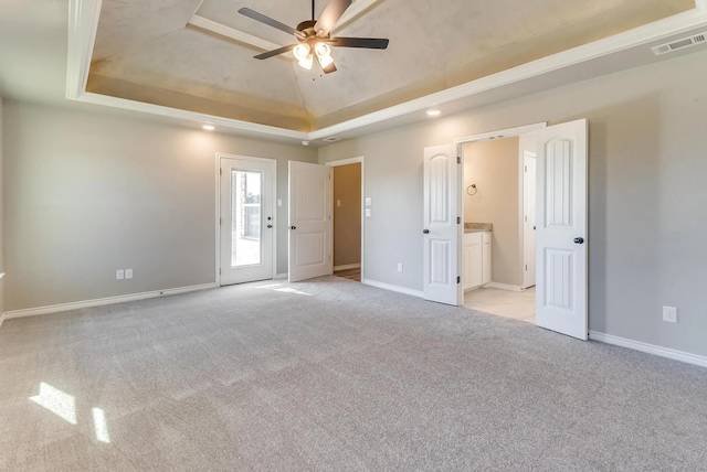 spare room with visible vents, baseboards, ceiling fan, light colored carpet, and a tray ceiling