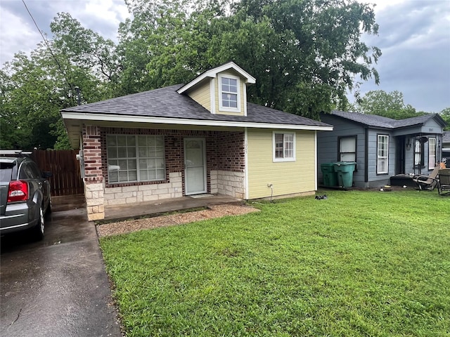 view of front of property featuring roof with shingles, fence, a porch, and a front yard