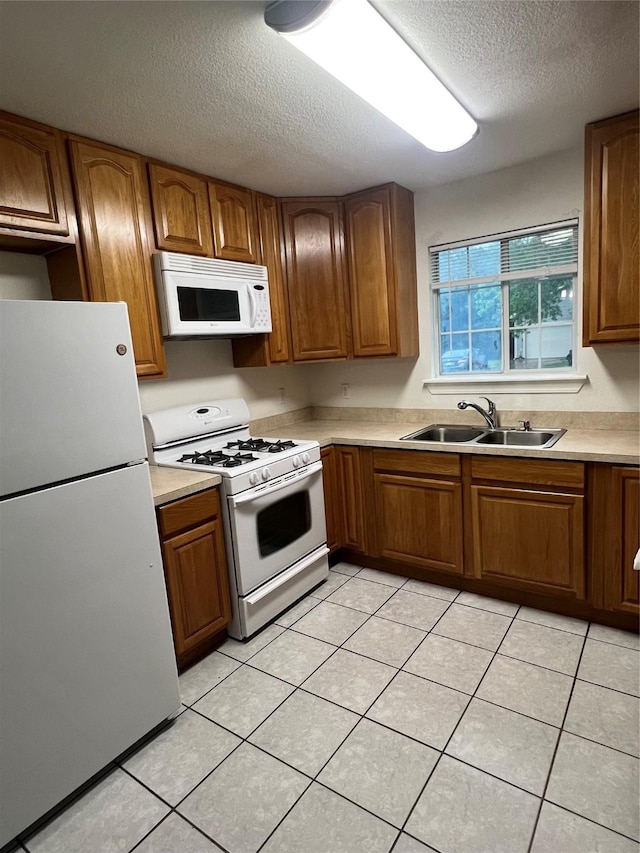 kitchen featuring a sink, brown cabinets, and white appliances
