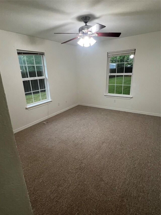 spare room with a healthy amount of sunlight, baseboards, ceiling fan, and carpet