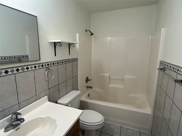 bathroom featuring tile walls, tile patterned floors, a wainscoted wall, toilet, and shower / bathtub combination