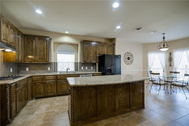 1290 Polo Heights Dr, Frisco, TX 75033 - kitchen with visible vents, light stone countertops, a center island, a sink, and stainless steel appliances