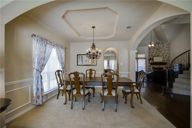 1290 Polo Heights Dr, Frisco, TX 75033 - dining area featuring visible vents, arched walkways, a fireplace, stairway, and ceiling fan with notable chandelier