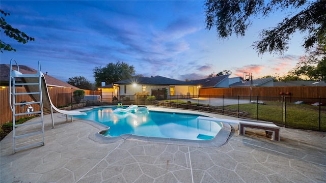 view of swimming pool featuring fence, a diving board, a water slide, a fenced in pool, and a patio area