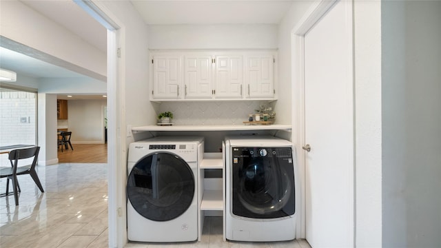 laundry room with separate washer and dryer, cabinet space, light tile patterned floors, and baseboards