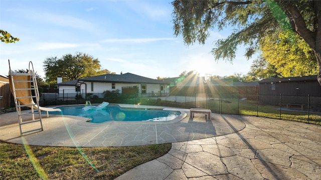 view of pool with a diving board, fence, a fenced in pool, a patio, and a water slide