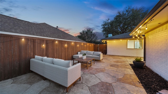 patio terrace at dusk with an outdoor living space and a fenced backyard