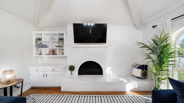 living area featuring vaulted ceiling with beams, wood finished floors, and a wealth of natural light