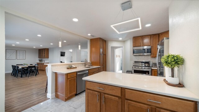 kitchen with backsplash, a peninsula, appliances with stainless steel finishes, and a sink