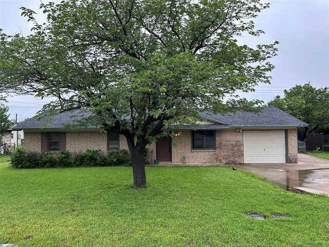 single story home with driveway, roof with shingles, a garage, brick siding, and a front lawn